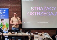 Seniorze poczuj się bezpiecznie. - Warsztaty o bezpieczeństwie dla seniorów.  Wykład strażaków. sala konferencyjna, seniorzy siedzą przy stołach, strażacy opowiadają, treść wyświetlona na ekranie. - powiększ