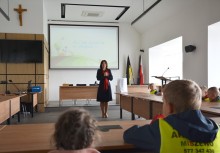 Wakacje z Urzędem Gminy Żukowo - Dzieci z Przedszkola z Miszewa w kamizelkach z opiekunkami, Sala konferencyjna Rady Miejskiej w Urzędzie Gminy w Żukowie, Pani Burmistrz Mariola Zmudzińska rozmawia z dziećmi. - powiększ