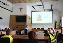 Wakacje z Urzędem Gminy Żukowo - Dzieci z Przedszkola z Miszewa w kamizelkach z opiekunkami, Sala konferencyjna Rady Miejskiej w Urzędzie Gminy w Żukowie, Pani sekretarz Natalia Sierakowska opowiada o Urzędzie. - powiększ