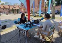 Piątek pełen wrażeń - Mobilne Studio Radia Gdańsk na dziedzińcu przy kościele pw. WNMP w Żukowie - przy stoliku, na którym są mikrofony Pani Burmistrz Mariola Zmudzińska oraz Magda Manasterska z Radia Gdańsk. - powiększ