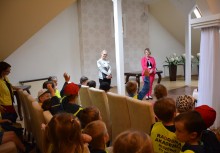 Wakacje z Urzędem Gminy Żukowo - Dzieci z Przedszkola z Miszewa w kamizelkach z opiekunkami, Sala ślubna Urzędu Stanu Cywilnego, sekretarz Natalia Sierakowska i kierownik Referatu Stanu Cywilnego Joanna Piełowska rozmawia z dziećmi. - powiększ