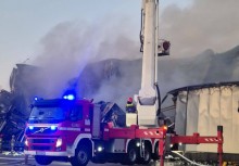 Wóz strażacki a w tle wielki palący się budynek - powiększ