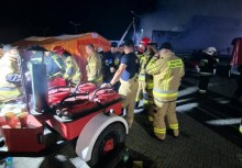 Strażacy serwujący jedzenie z kuchni polowej innym pracującym strażakom - powiększ