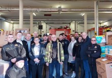 Około 20 osób w remizie strażackiej, w tle pojazd straży pożarnej, dookoła kartony - powiększ