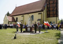Na pierwszym planie pomnik Matki Boskiej Królowej Polski, obok flagi Polski i Kaszub. W tle delegacje ze sztandarami oraz kościół pw. św. Jana w Żukowie - powiększ