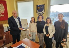 Burmistrz Wojciech Kankowski z trzema uczennicami i nauczycielką. W ręku trzyma certyfikat - powiększ
