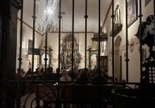 Zwiedzanie z przewodnikiem wnętrza Kościoła św. Jana Chrzciciela w Żukowie – uczestnicy Nocy Muzeów siedzą w ławkach, widok przez kutą kratę na barokowy ołtarz i historyczne wnętrze świątyni. - powiększ