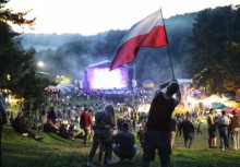 Zdjęcie z oddali na koncert na pierwszym planie mężczyzna z flaga Polski  - powiększ