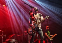 Na scenie mężczyzna trzymający gitarę  - powiększ