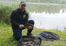 Wędkarz kucający z rybą w dłoni - powiększ
