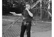 Czarno biała fotografia mężczyzny trzymającego mikrofon.