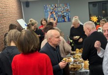 Poczęstunek na stołach w świetlicy, wokół ludzie - powiększ