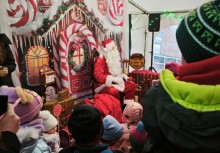 Mikołaj siedzi na krześle, wokół niego dzieci - powiększ