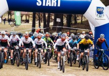 Grupa kolarzy rusza spod bramy z napisem 'START'. - powiększ
