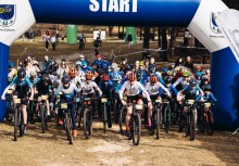 Grupa kolarzy rusza spod bramy z napisem 'START'. - powiększ