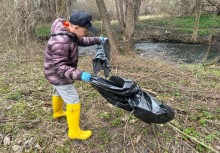 Dziecko trzymające w ręku worek, podczas sprzątania - powiększ