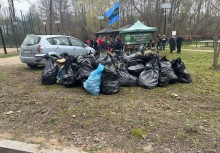 Na pierwszym planie worki z zebranymi odpadami. W tle grupa osób. - powiększ