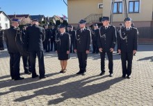 Grupa strażaków w galowych mundurach podczas uroczystości na placu.  - powiększ