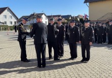 Sześciu strażaków podczas uroczystej dekoracji medalami. W tle widać pozostałych funkcjonariuszy stojących w rzędzie.  - powiększ