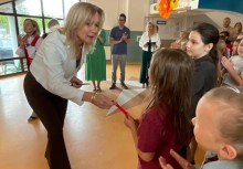 Kobieta pochyla się nad dziewczynką. W tle widać innych uczestników wydarzenia. - powiększ