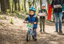Na pierwszym planie chłopiec na rowerze, z tyłu dwie osoby z mapami - powiększ