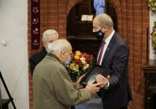 Burmistrz składa kwiaty i tabliczkę pamiątkową na ręce dwóch reprezentantów chóru Harmonia