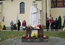 Pomnikiem Matki Boskiej Królowej Polski. Na nim złożone kwiaty, w tle dwa poczty sztandarowe.