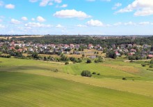 Panorama Gminy Żukowo – widok z lotu ptaka na rozległe tereny zielone i zabudowę mieszkalną. W tle widoczne centrum miejscowości z kościołem i niską zabudową.