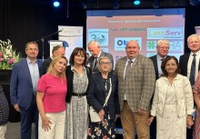 Burmistrz Mariola Zmudzińska z uczestnikami konferencji lokalnej – wspólne zdjęcie na tle ekranu z logotypami partnerów wydarzenia. - powiększ