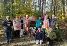 Na zdjęciu dzieci ze szkoły podstawowej z nauczycielką przed pomnikiem - powiększ