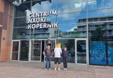 Trzy osoby przed wejściem do Centrum Nauki Kopernik w Warszawie – nowoczesny budynek z przeszkloną fasadą i charakterystycznym napisem nad drzwiami. - powiększ