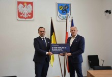 Poseł Marcin Horała i Burmistrz Wojciech Kankowski trzymają tabliczkę z nazwą inwestycji i kwotą dofinansowania. W tle flagi Kaszub, Polski i Unii Europejskiej. Nad nimi Godło Polski i Herb Gminy Żukowo.