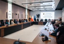 Osoby siedzące przy stołach. W tle prezentacja - powiększ