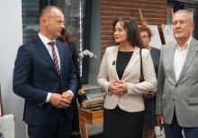 Grupa osób w eleganckich strojach rozmawia podczas wydarzenia kulturalnego; na pierwszym planie kobieta i dwóch mężczyzn. - powiększ