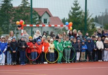 Kolorowy rząd uczniów z obręczami na tle bramki udekorowanej balonami - powiększ