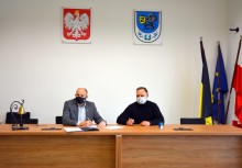 W sali Rady Miejskiej w Żukowie burmistrz oraz przedstawiciel wykonawcy inwestycji siedzą przy stole. Burmistrz podpisuje umowę. - powiększ
