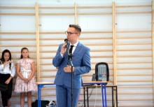 Dyrektor szkoły przemawia podczas uroczystości w nowej sali gimnastycznej – w tle uczniowie i pracownicy placówki. - powiększ