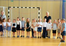 Grupa najmłodszych uczniów z wychowawcami podczas uroczystości rozpoczęcia roku szkolnego – wydarzenie w sali gimnastycznej. - powiększ