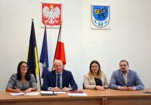 Skarbnik, Burmistrz oraz przedstawiciele wykonawcy inwestycji przy biurku w sali Rady Miejskiej - powiększ