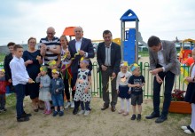 Dorośli i dzieci przecinają wstęgę - powiększ