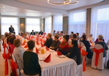 Przy stole panie z Kół Gospodyń Wiejskich trzymają kwiaty, Burmistrz przemawia - powiększ