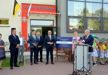 Burmistrz Gminy Żukowo przemawia, za nim dzieci w strojach z kaszubskimi akcentami. Obok niego 7 osób - powiększ