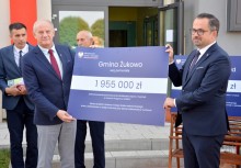 Burmistrz Gminy Żukowo i Wiceminister Funduszy i Polityki Regionalnej trzymają symboliczny czek z kwotą 1 955 000 zł  - powiększ