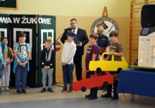 Przedstawienie artystyczne, niektórzy chłopcy trzymają tekturowe samochody - powiększ