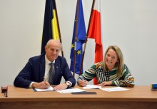 Burmistrz oraz wykonawca podpisują umowę, w tle flagi Kaszub, Unii Europejskiej i Polski