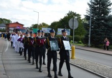 Kondukt żałobny, na pierwszym planie strażacy niosący zdjęcia zmarłych druhów - powiększ
