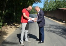 Burmistrz oraz kierownik referatu inwestycji Urzędu Gminy w Żukowie przeglądają dokumenty na zmodernizowanej drodze - powiększ