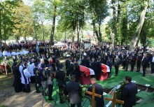 Dwie trumny z polskimi flagami na cmentarzu, dookoła tłum ludzi - powiększ