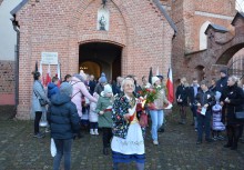 Mieszkańcy wychodzący z kościoła trzymający w rękach flagi Polski - powiększ