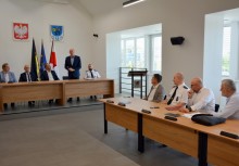 9 osób przy stołach w sali Rady Miejskiej w Urzędzie Gminy w Żukowie. Burmistrz przemawia - powiększ